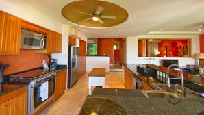 Une cuisine moderne dotée d’appareils électroménagers en acier inoxydable, de meubles en bois et d’un îlot central.