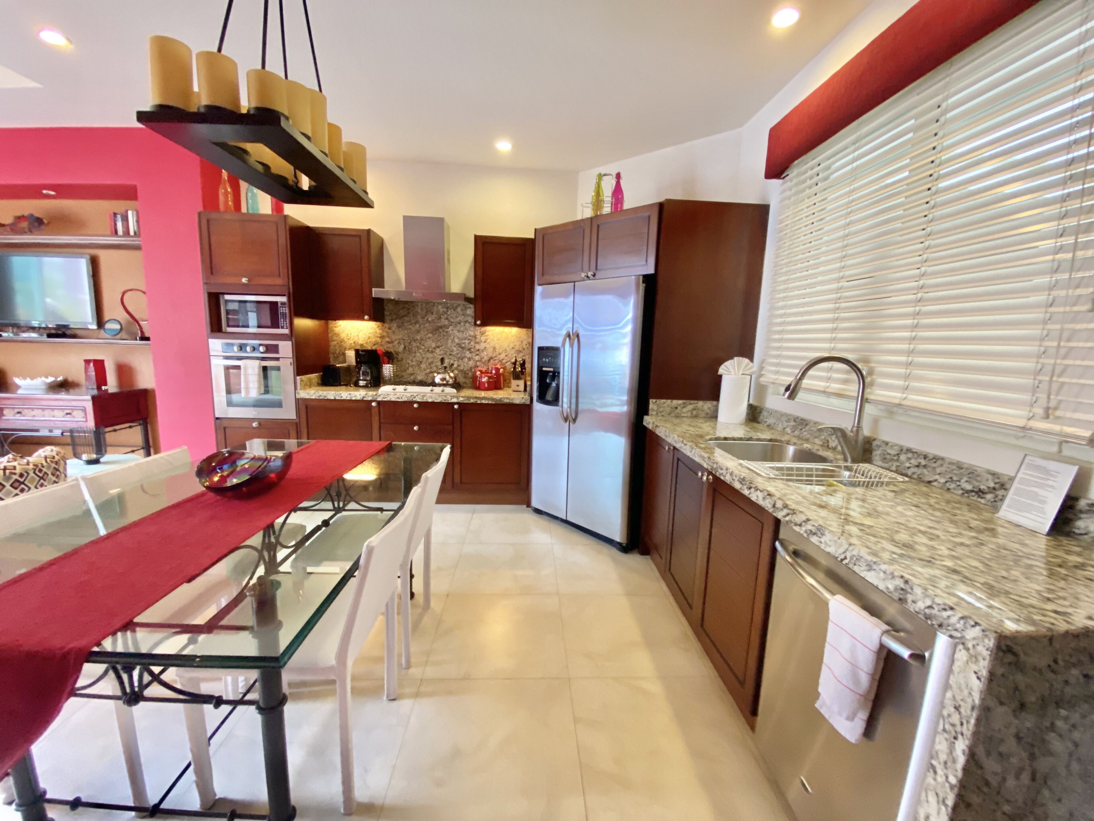 A modern kitchen with granite countertops, stainless steel appliances, and a dining area with a glass table and chairs.