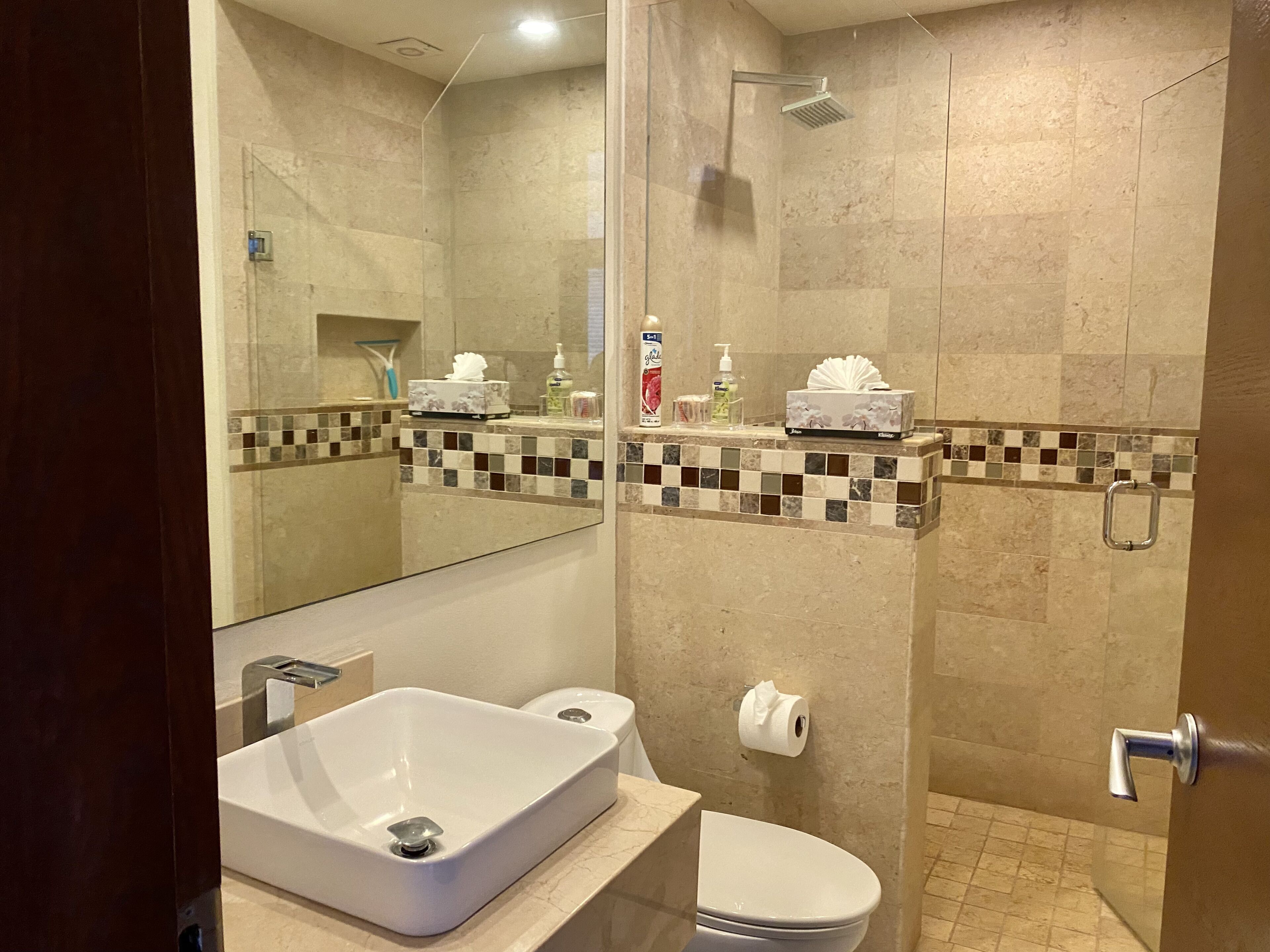 Ein modernes Badezimmer mit großem Spiegel, Waschbecken in Weiß, Toilette und Duschbereich.
