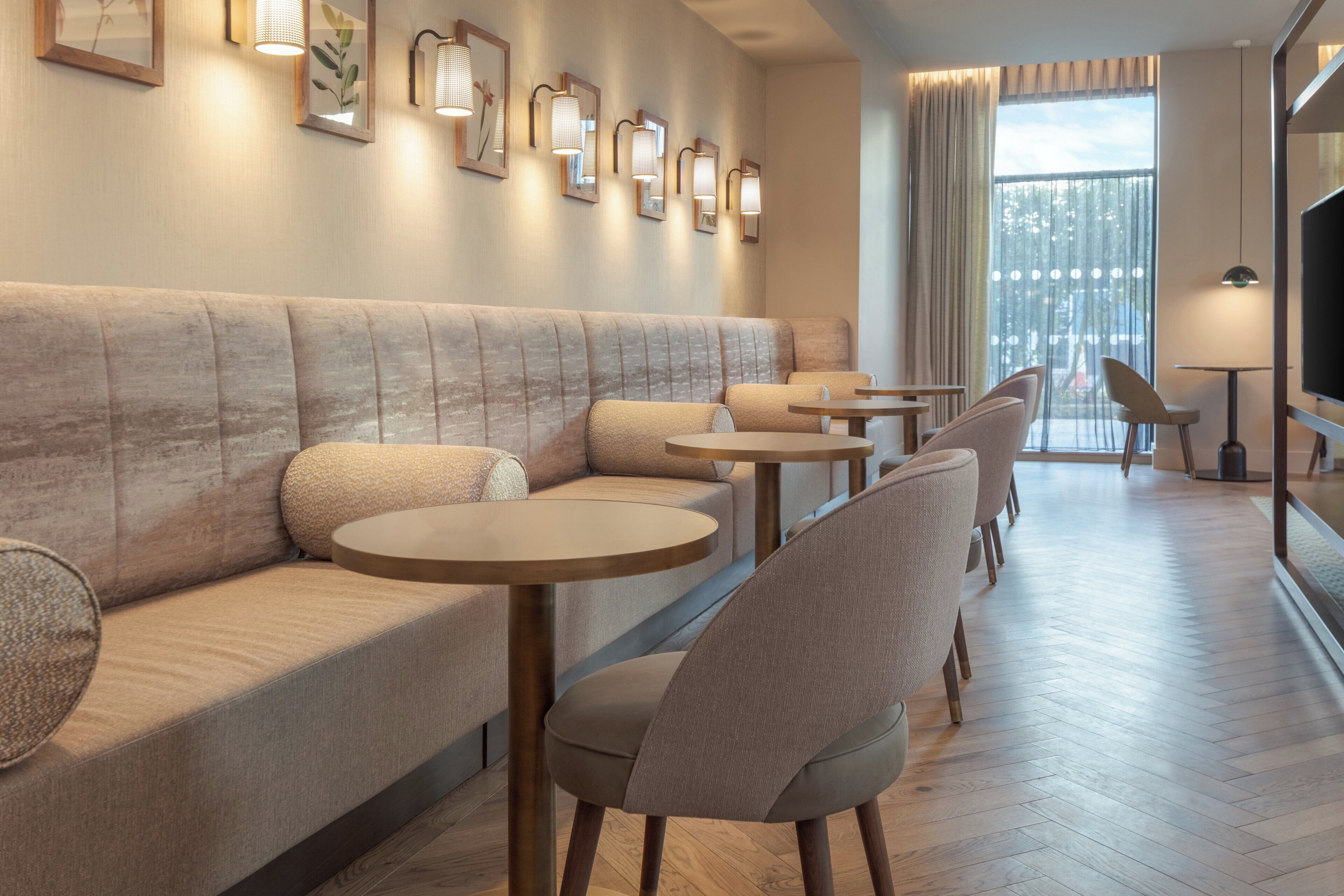 Un espace de détente moderne comprenant un canapé, des fauteuils et des tables, et doté d’une grande fenêtre offrant une vue imprenable.