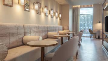 Ein stilvoller Lounge-Bereich mit einer Couch, Sesseln und Tischen, mit einem großen Fenster und Blick.