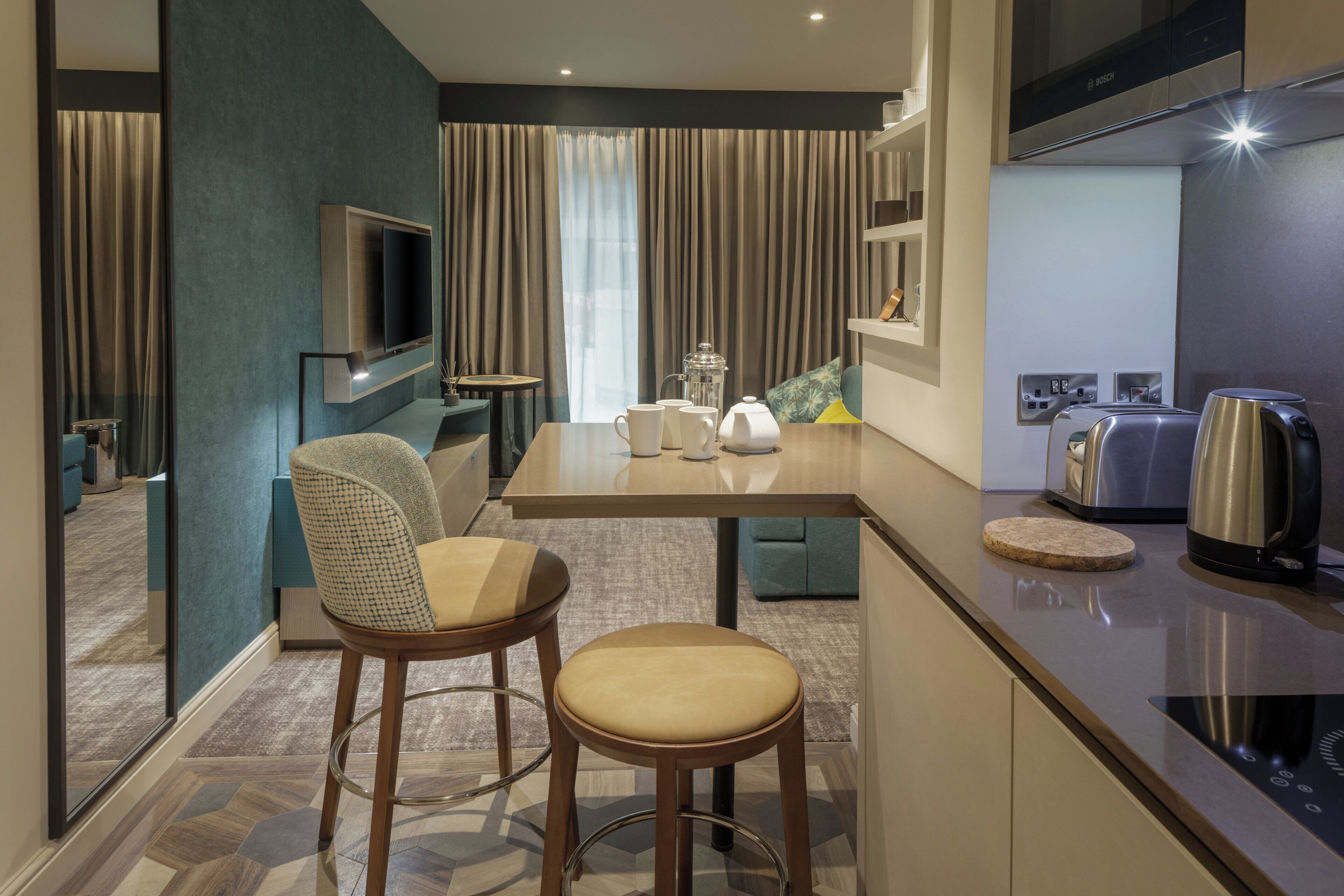 Una habitación de hotel moderna con comedor, cocina y televisor.