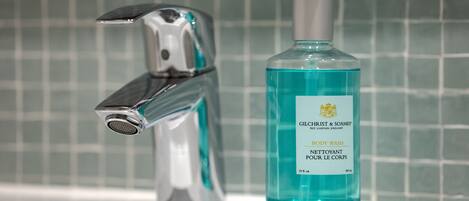 A bathroom with a chrome faucet and a bottle of Gilchrist & Soames body wash.