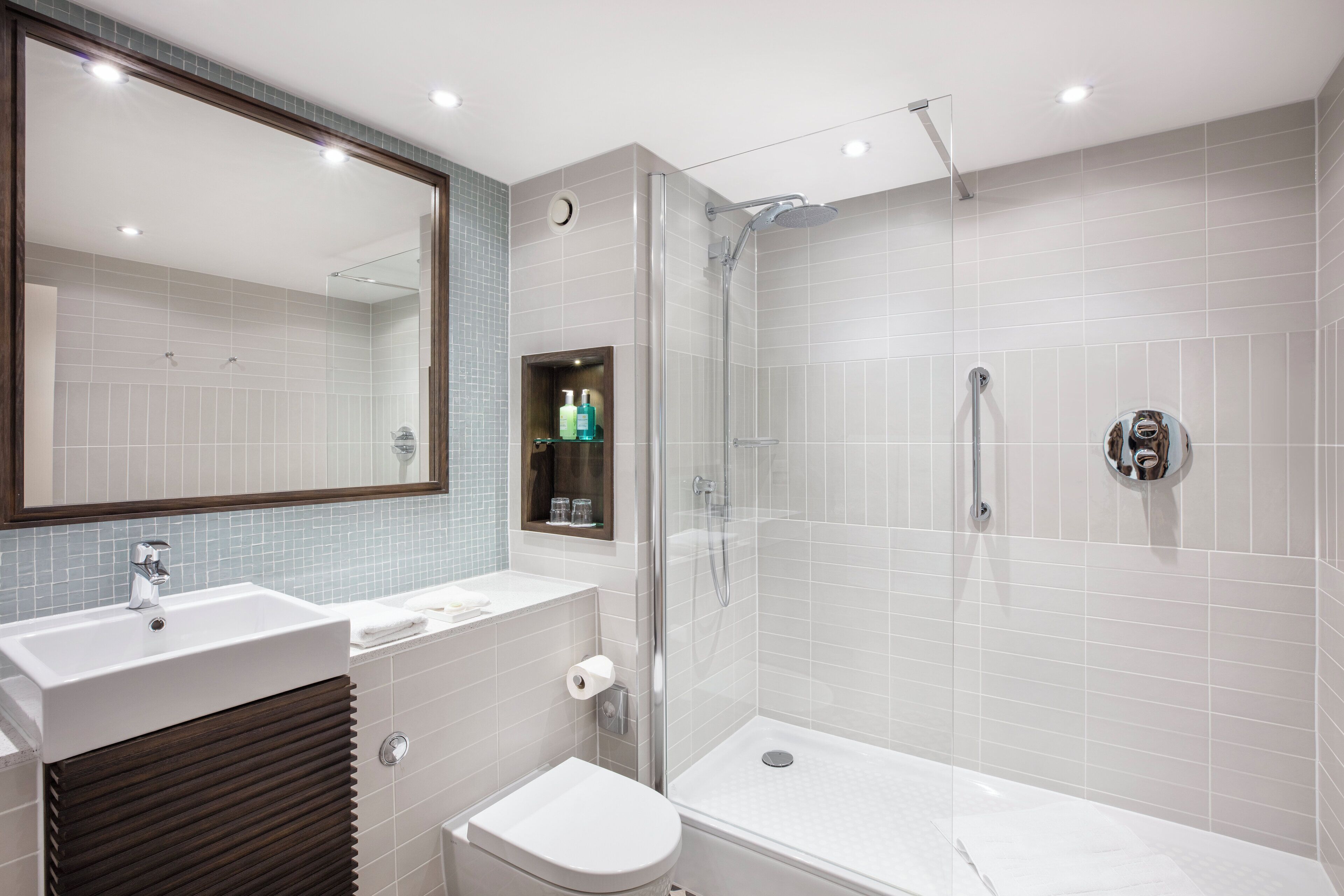 Un baño moderno con lavamanos, inodoro y ducha.