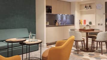 Un salon moderne comprenant un canapé, deux fauteuils, une table basse et un coin repas avec une table et des chaises.