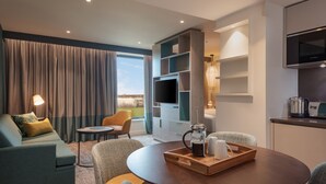 A modern living room with a sofa, chairs, a coffee table, and a TV. - Staybridge Suites London Heathrow - Bath Road by IHG (West Drayton)