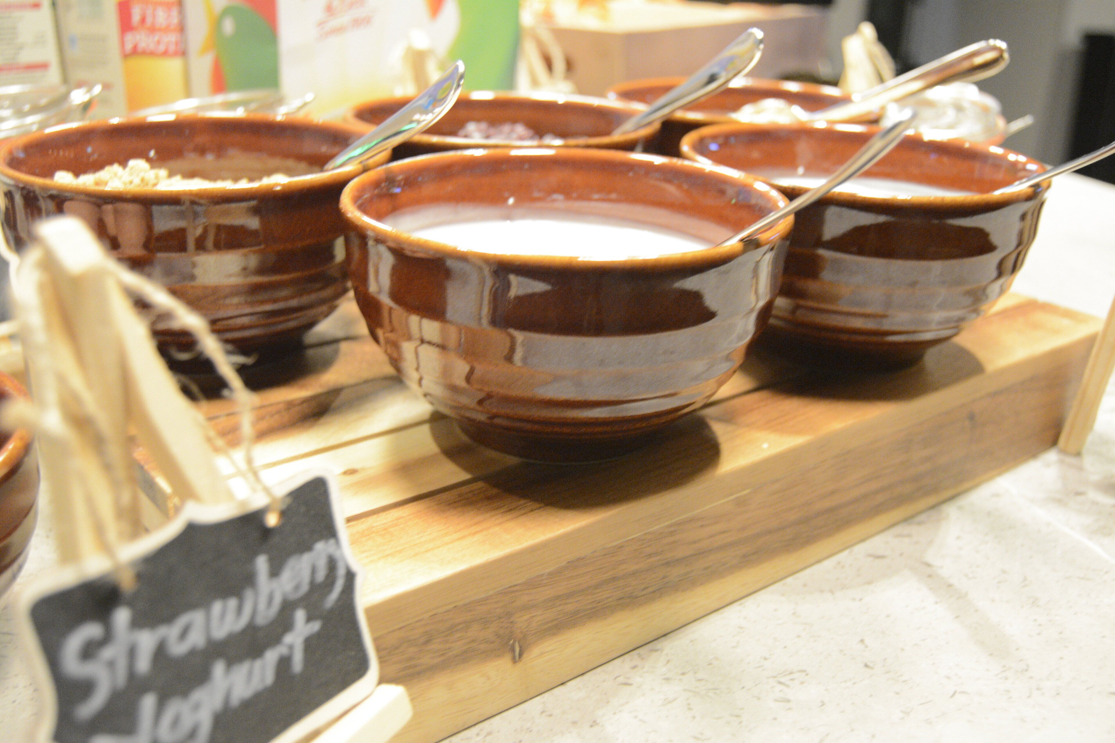 Bowls of strawberry yogurt on a wooden board.