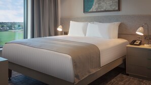 A hotel room with a large bed, two bedside lamps, a telephone, and a painting on the wall. - Staybridge Suites London Heathrow - Bath Road by IHG (West Drayton)