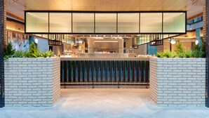 A modern interior with a central kitchen area, a seating area with a glass partition, and a staircase leading to an upper level. - Holiday Inn London Heathrow - Bath Road by IHG (West Drayton)