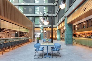 Un espacio interior amplio con una mesa central rodeada de sillas, una barra a la derecha y una zona de estar a la izquierda.