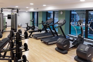 Un gimnasio con cintas de correr, elípticas y máquinas de pesas.