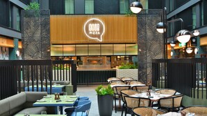 An indoor dining area with tables and chairs, a pizza restaurant sign, and a modern interior design. - Holiday Inn London Heathrow - Bath Road by IHG (West Drayton)