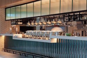 A modern kitchen with a brick wall, a stainless steel countertop, and a variety of kitchen appliances and utensils.
