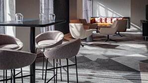 A modern hotel room with a dining area, a sofa set, and a TV. - Holiday Inn London Heathrow - Bath Road by IHG (West Drayton)