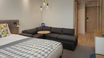 A hotel room with a bed, a sofa, a small round table, and a blue octopus decoration.