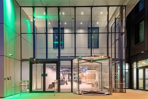 A modern building entrance with glass doors and a revolving door. - Holiday Inn London Heathrow - Bath Road by IHG (West Drayton)