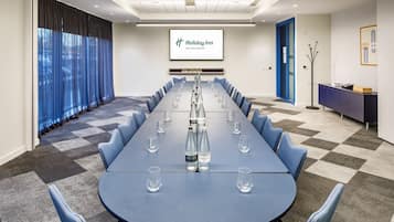 A conference room with a long table, chairs, and a screen displaying the Holiday Inn logo.