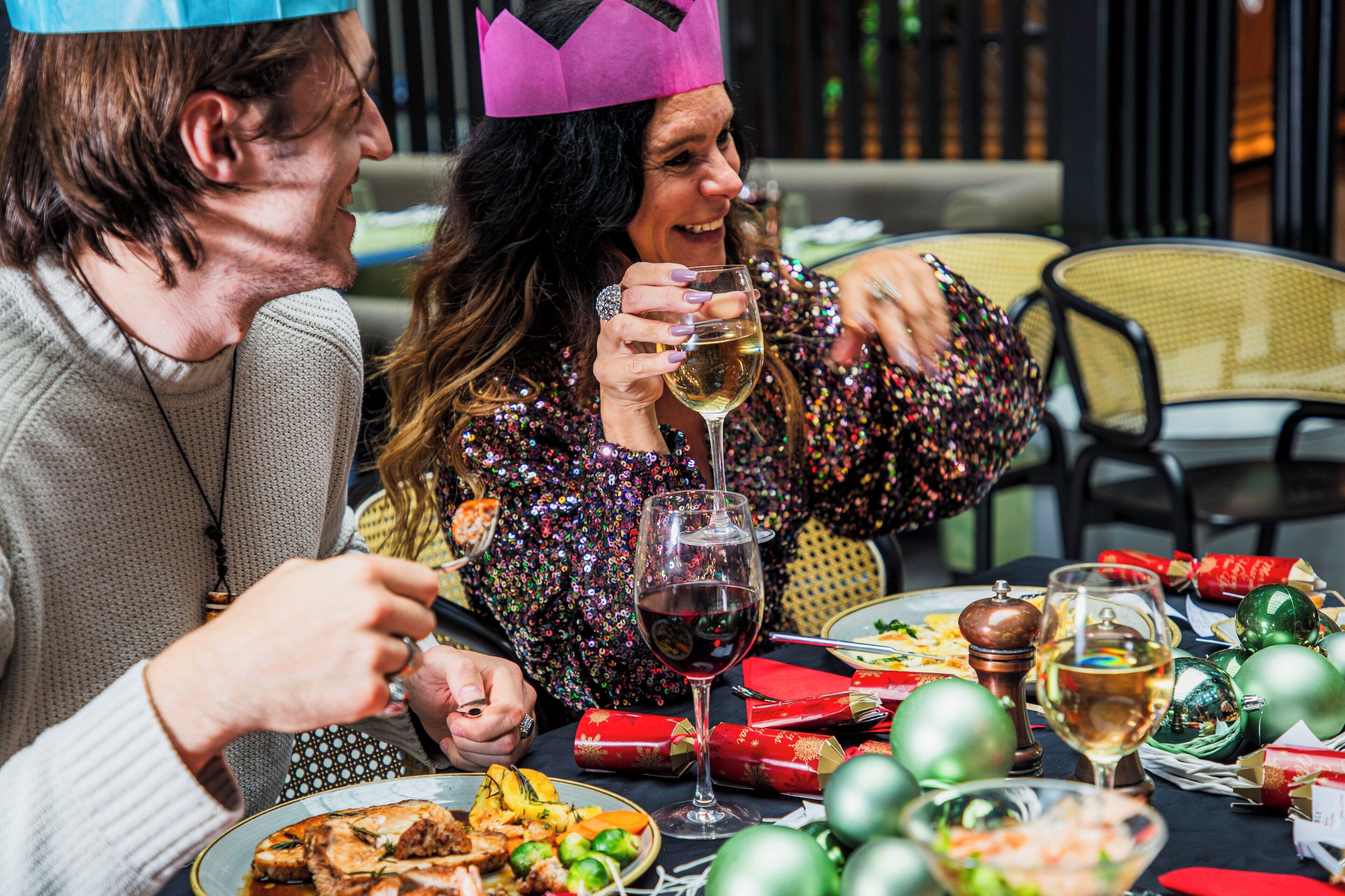 A dining table set with food, wine glasses, and Christmas decorations.