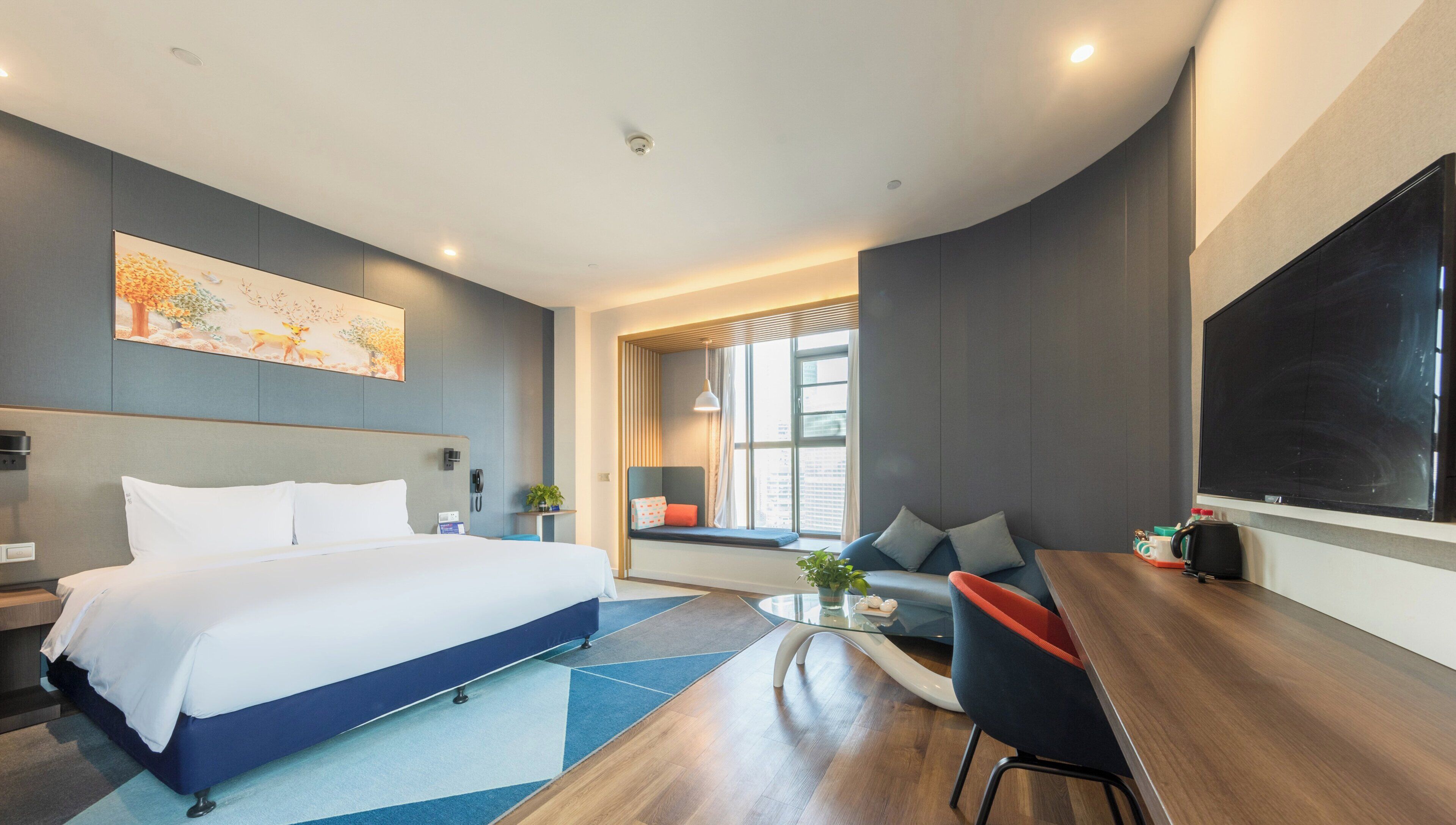 Une chambre d’hôtel moderne dotée d’un grand lit, d’un bureau avec une chaise, d’une télévision et d’une fenêtre donnant sur la ville.