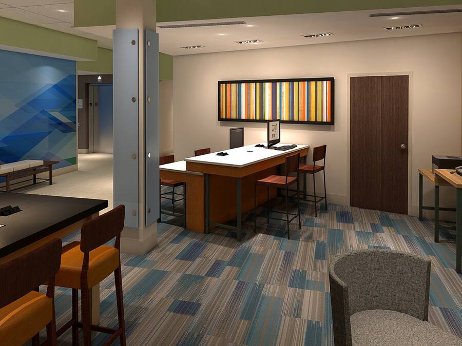A modern hotel room with a desk, chairs, a computer, and a flat-screen TV.