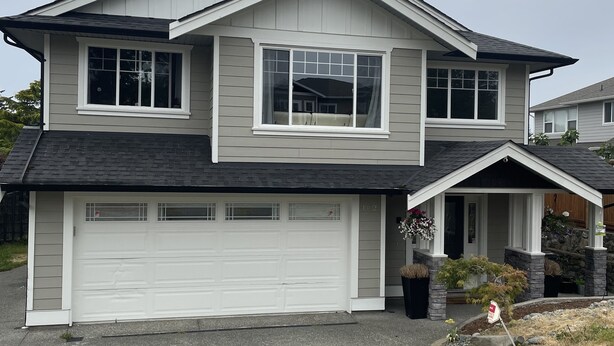 A two-story house with a garage, a front porch, and a small garden area. - Starting Point Family House (Victoria)