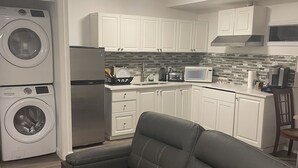A compact living space with a sofa, washing machine, refrigerator, microwave, and tiled backsplash. - Starting Point Family House (Victoria)