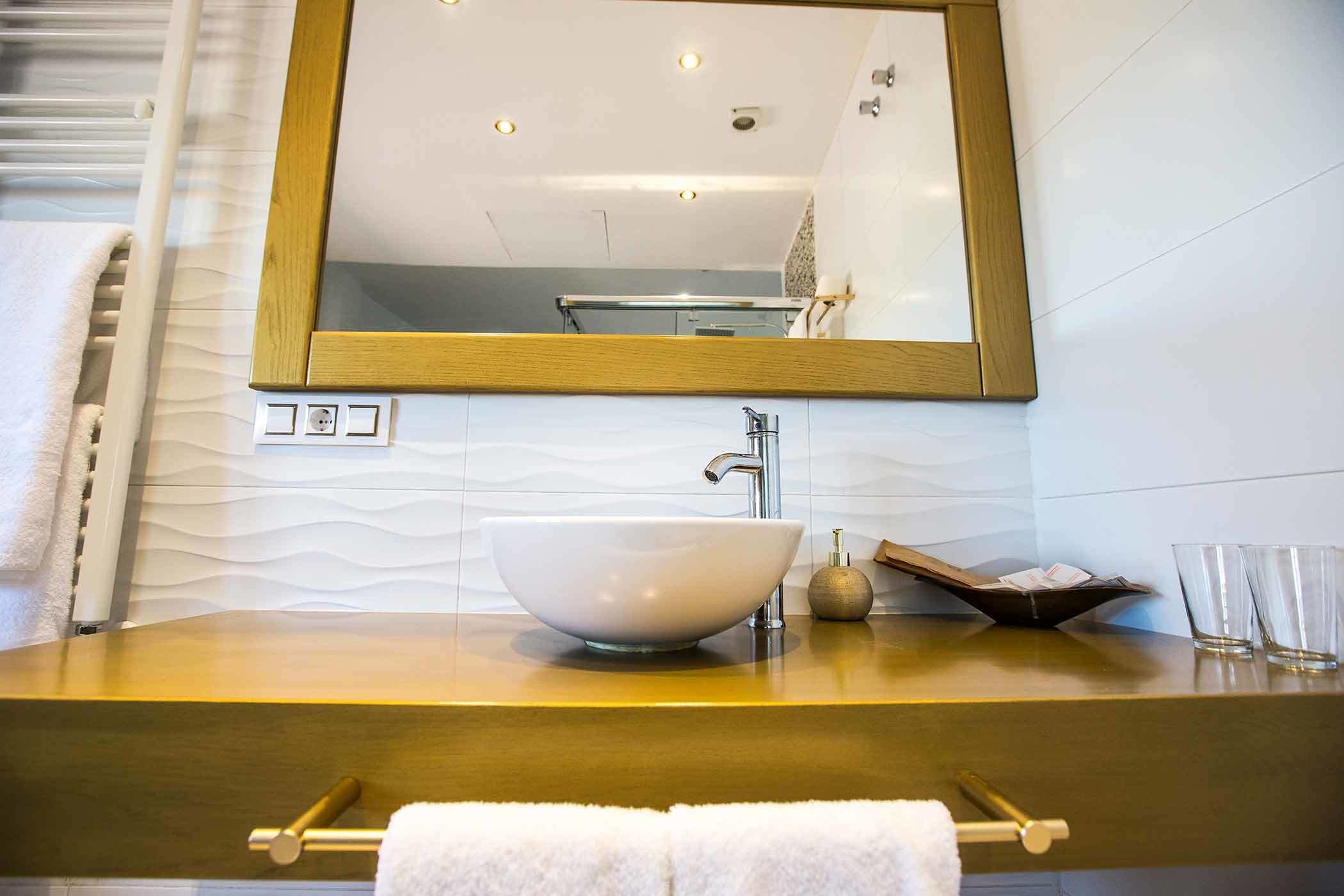 Un bany amb un mirall gran, un lavabo blanc i una barra de tovalloles.