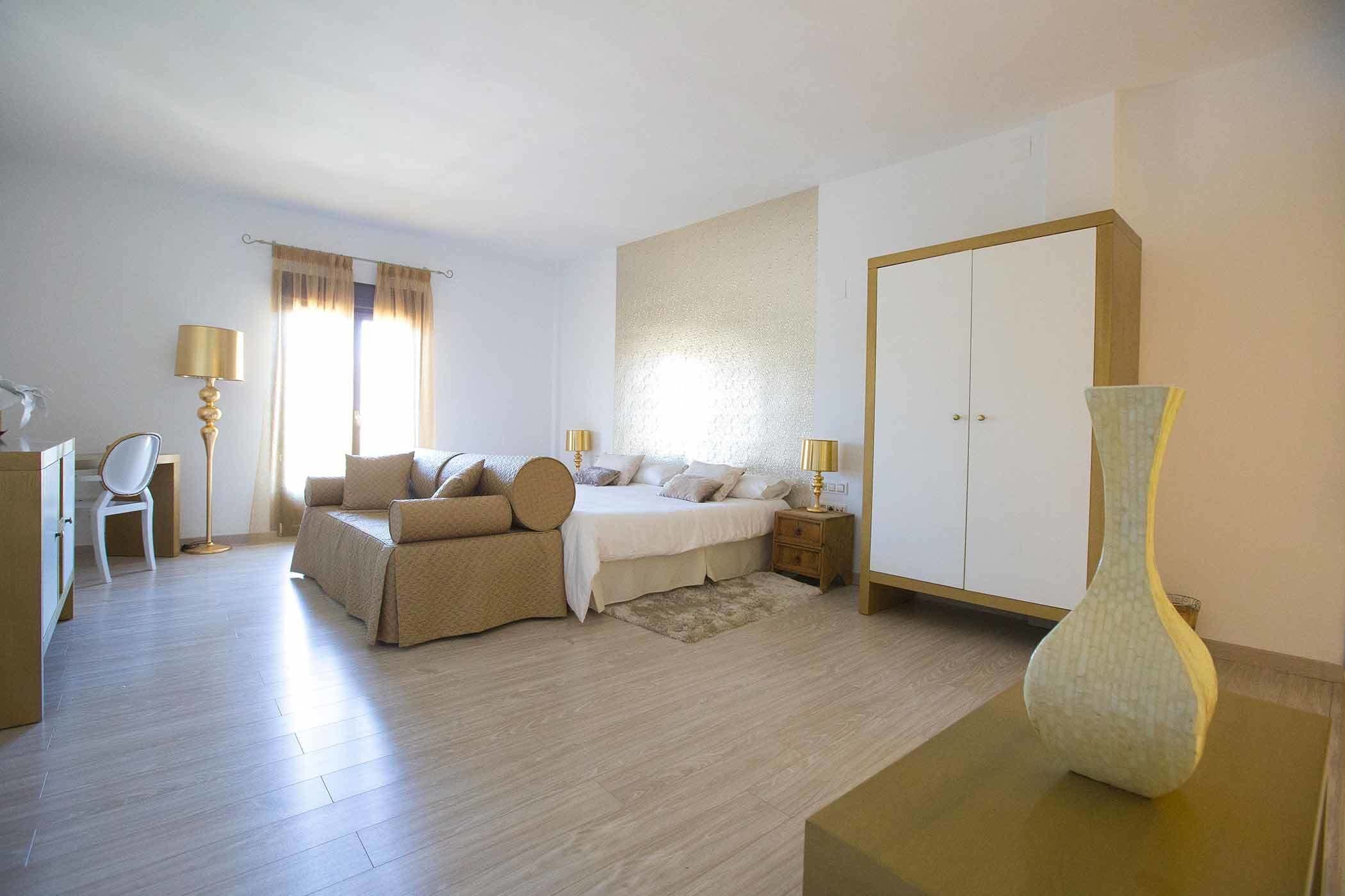 A bedroom with a bed, bedside tables, a wardrobe, a chair, and a lamp.