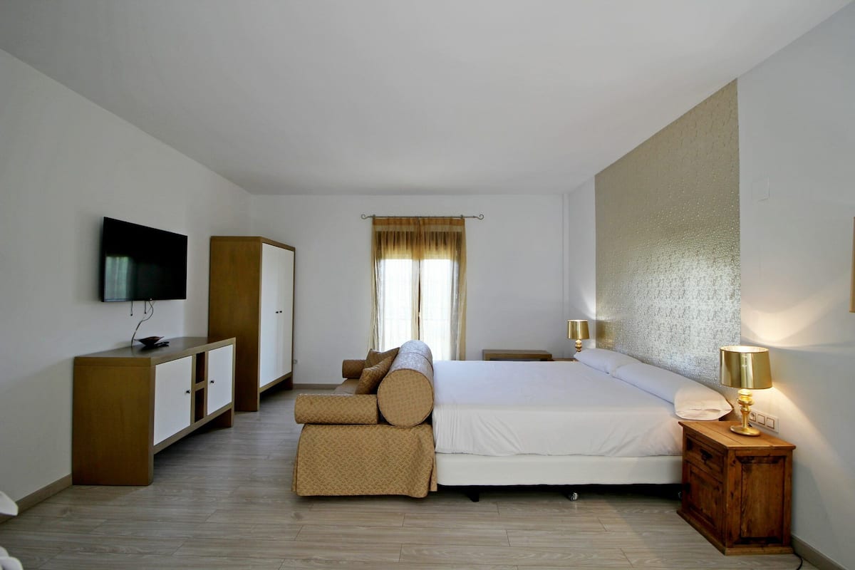 A bedroom with a bed, a TV, a wardrobe, a bedside table, and a lamp.