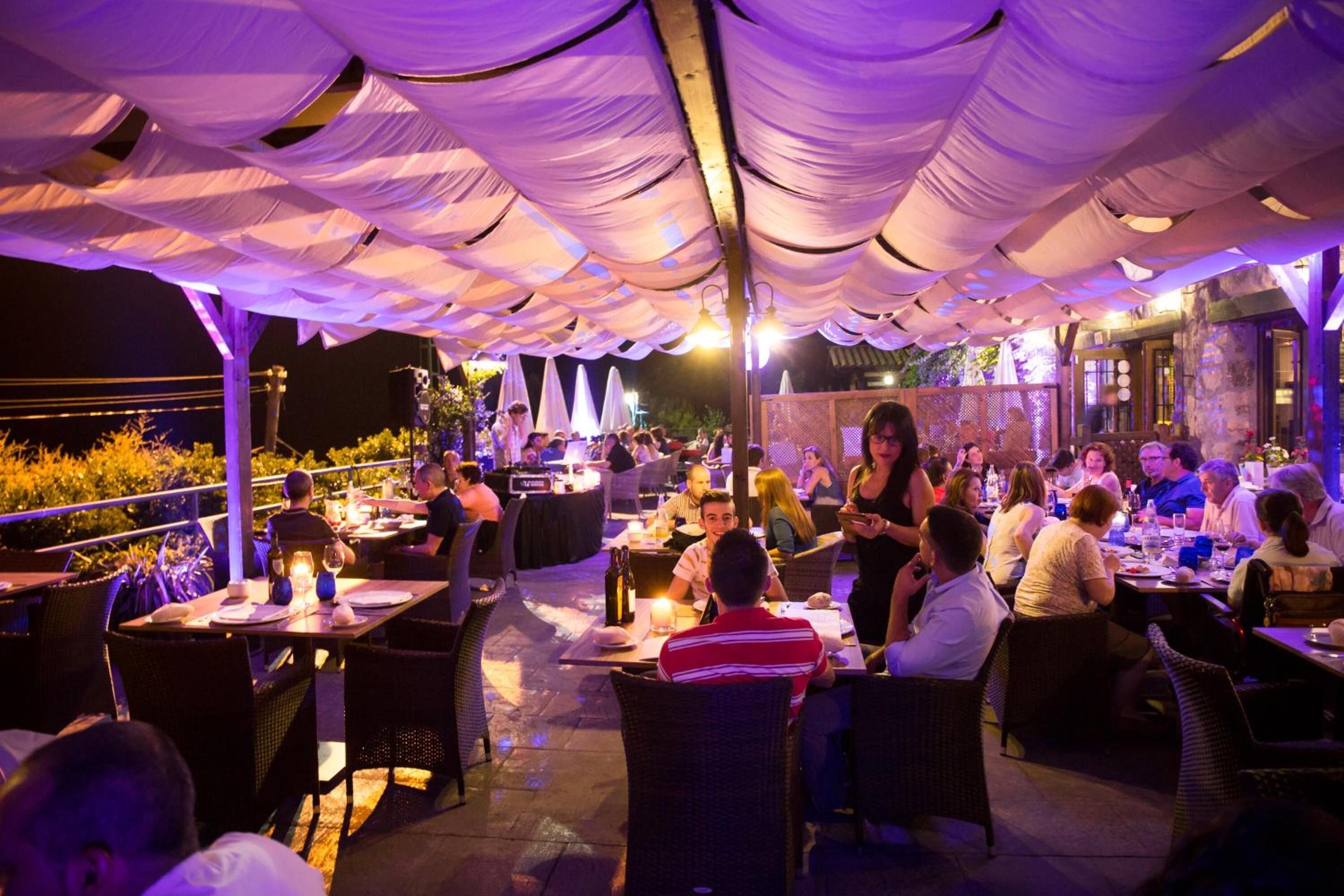 An outdoor dining area with tables and chairs under a canopy.