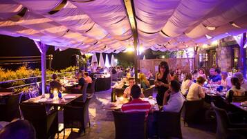 An outdoor dining area with tables and chairs under a canopy.