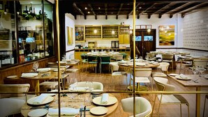 A restaurant with round tables, chairs, and a bar area with shelves of bottles and glasses. - Villa Xarahiz (Jaraíz de la Vera)