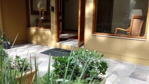 A hotel entrance with a tiled pathway, potted plants, and a wooden chair outside. - Locar-in Gramado Vista verde e perto de Tudo (Gramado)
