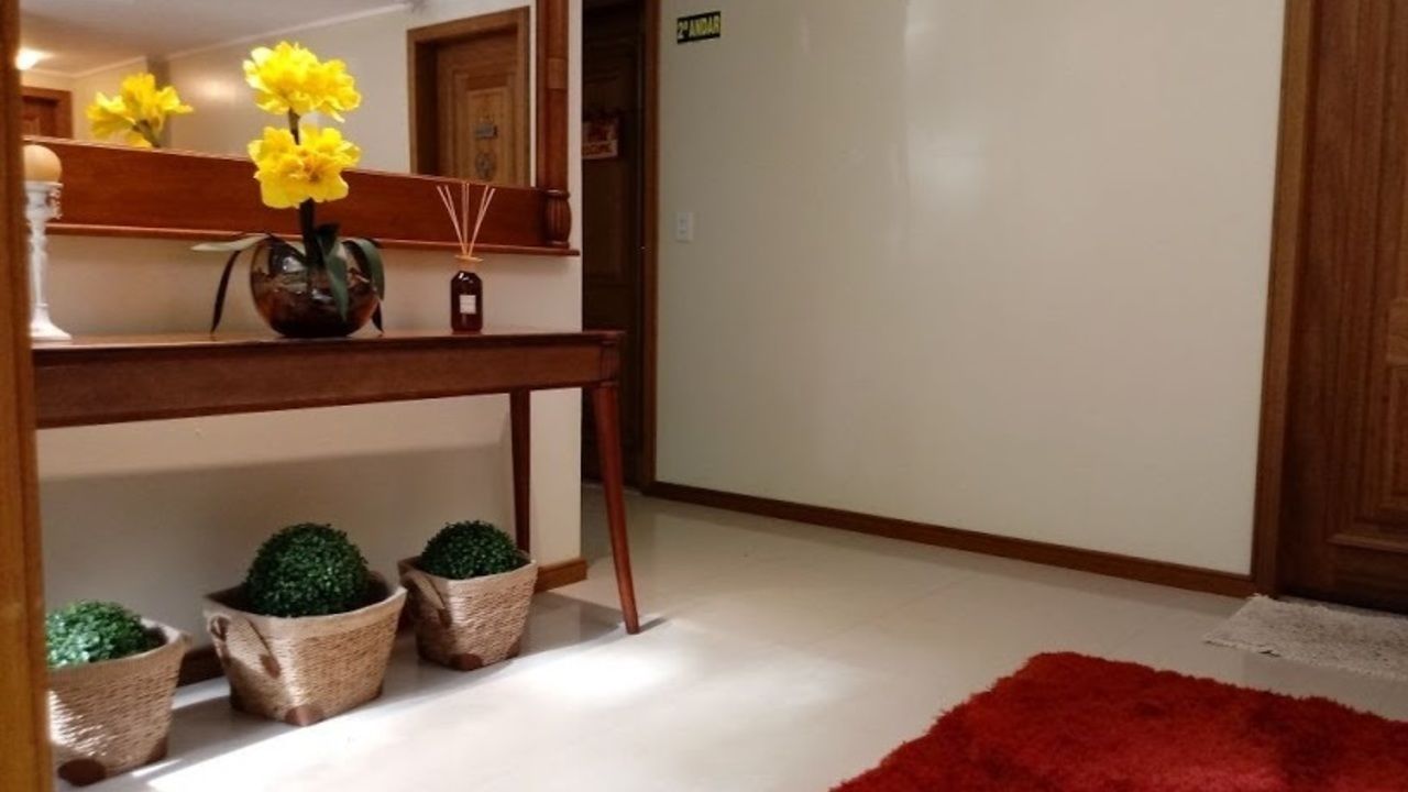 A hallway with a wooden console table, a mirror, and potted plants.