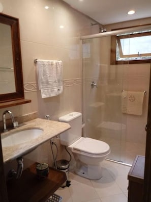 Une salle de bain avec une douche à parois de verre, des toilettes et un lavabo avec un miroir au-dessus.
