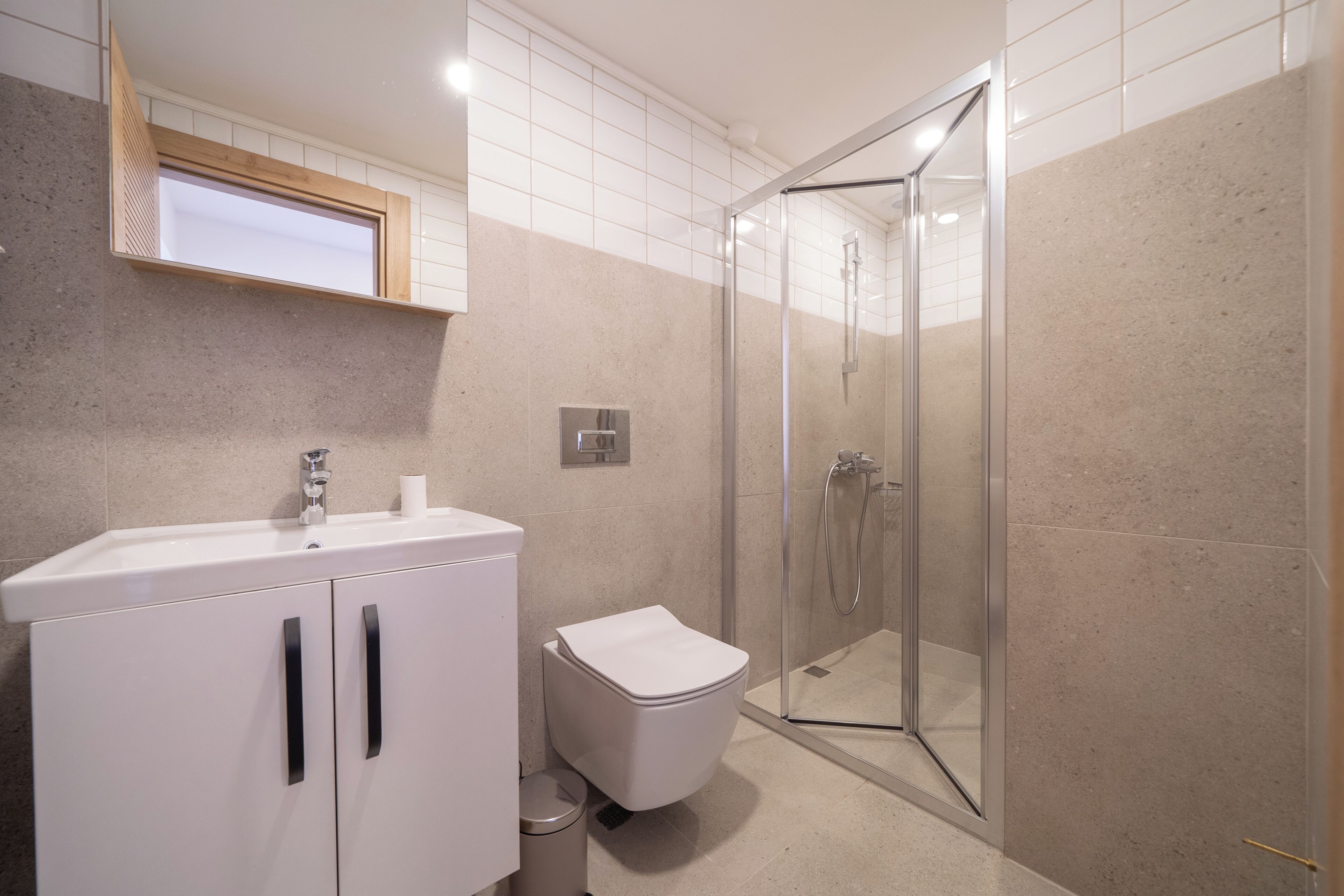 A modern bathroom with a white sink, toilet, and glass-enclosed shower.