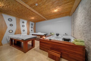Un cuarto de spa con bancos de madera, una bañera grande y un tocador de madera con toallas.