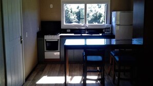 Una cocina compacta con ventana, un refrigerador y una estufa.