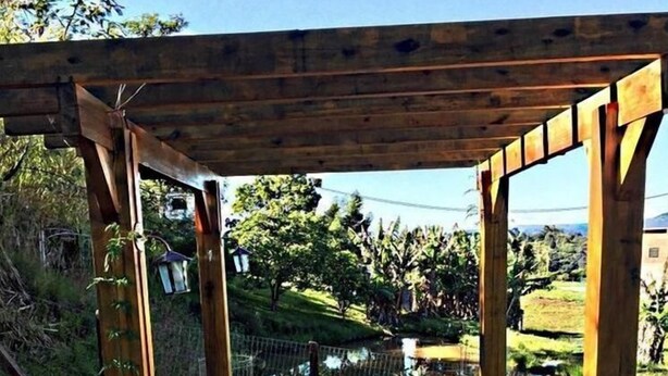 Una estructura de pérgola de madera con una zona de asientos que incluye cuatro taburetes.