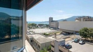 A view from a window overlooking a cityscape with buildings and a distant mountain. - Dreamcatchers (La Spezia)