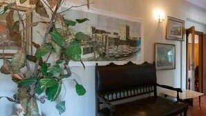 A room with a black bench, a wall-mounted picture, and a hanging plant. - Dreamcatchers (La Spezia)