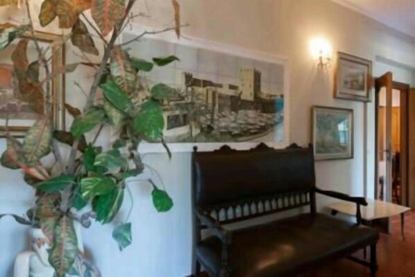 A room with a black bench, a wall-mounted picture, and a hanging plant.