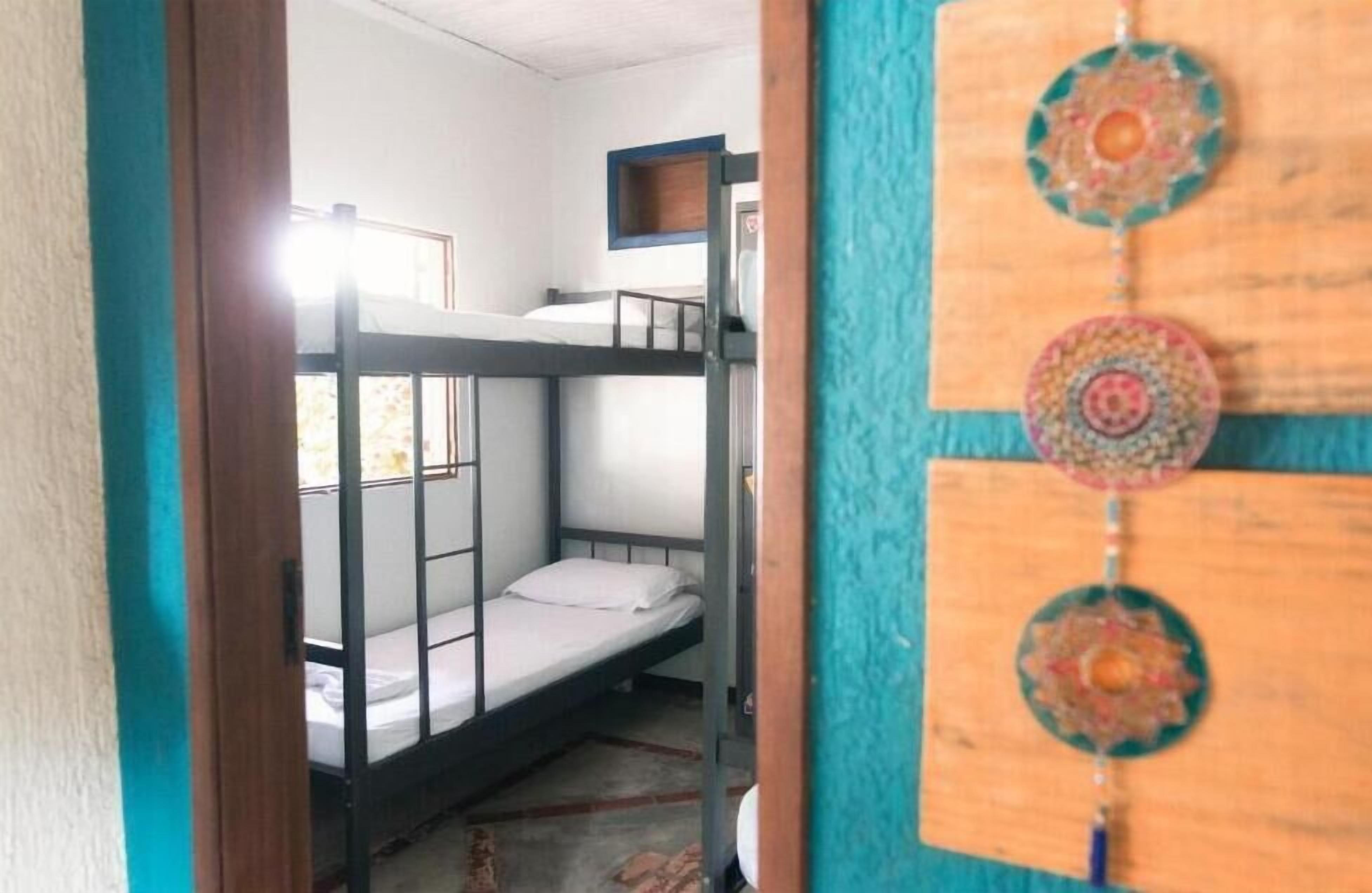 A bunk bed room with a wooden door and a colorful wall hanging.