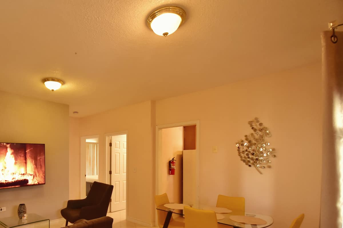 A living room with a flat-screen TV, a sofa, and a dining area with a table and chairs.