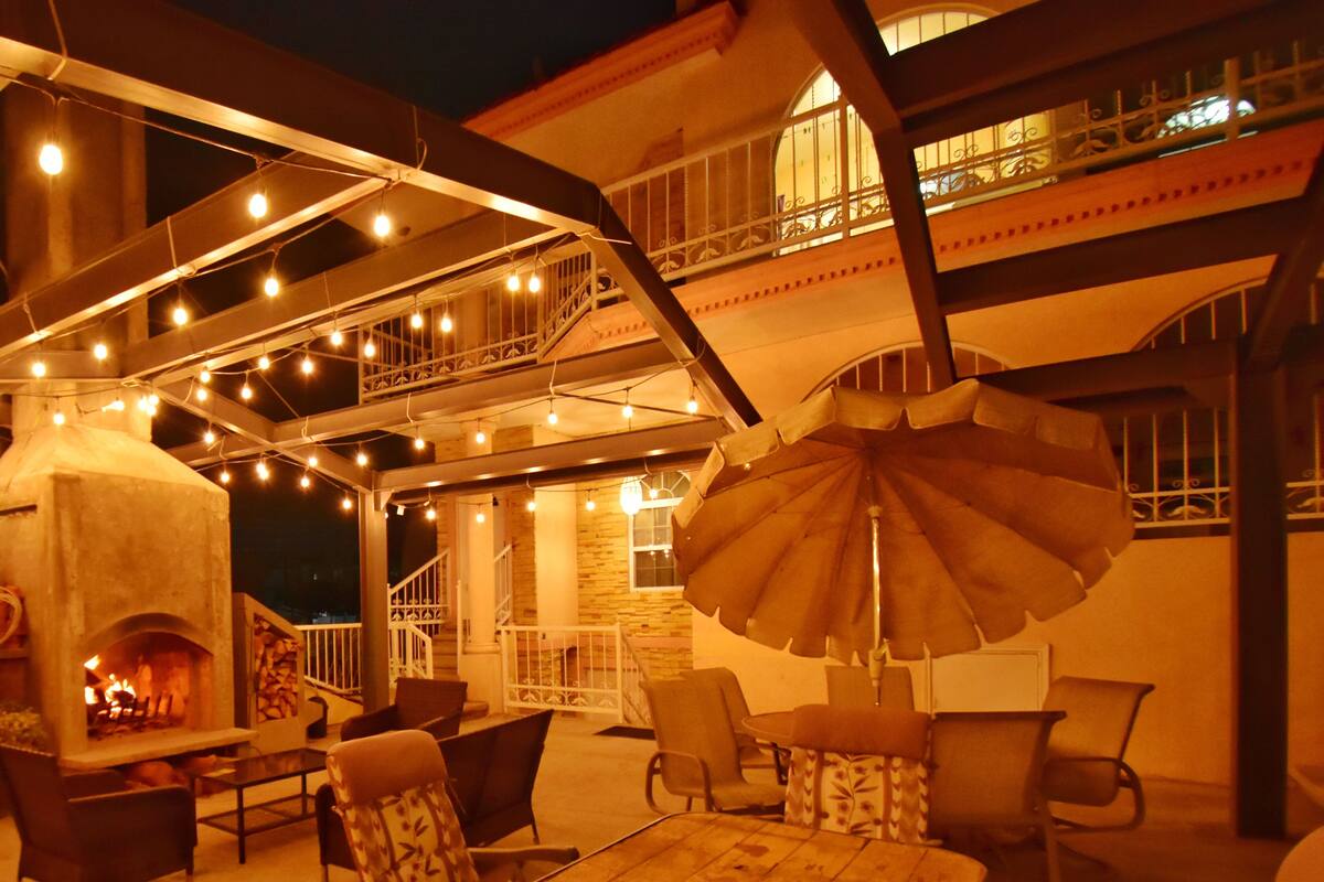 An outdoor patio with a stone fireplace, string lights, and outdoor furniture.