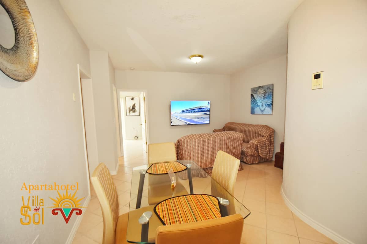 A hotel room with a dining area, a television, and a bed.