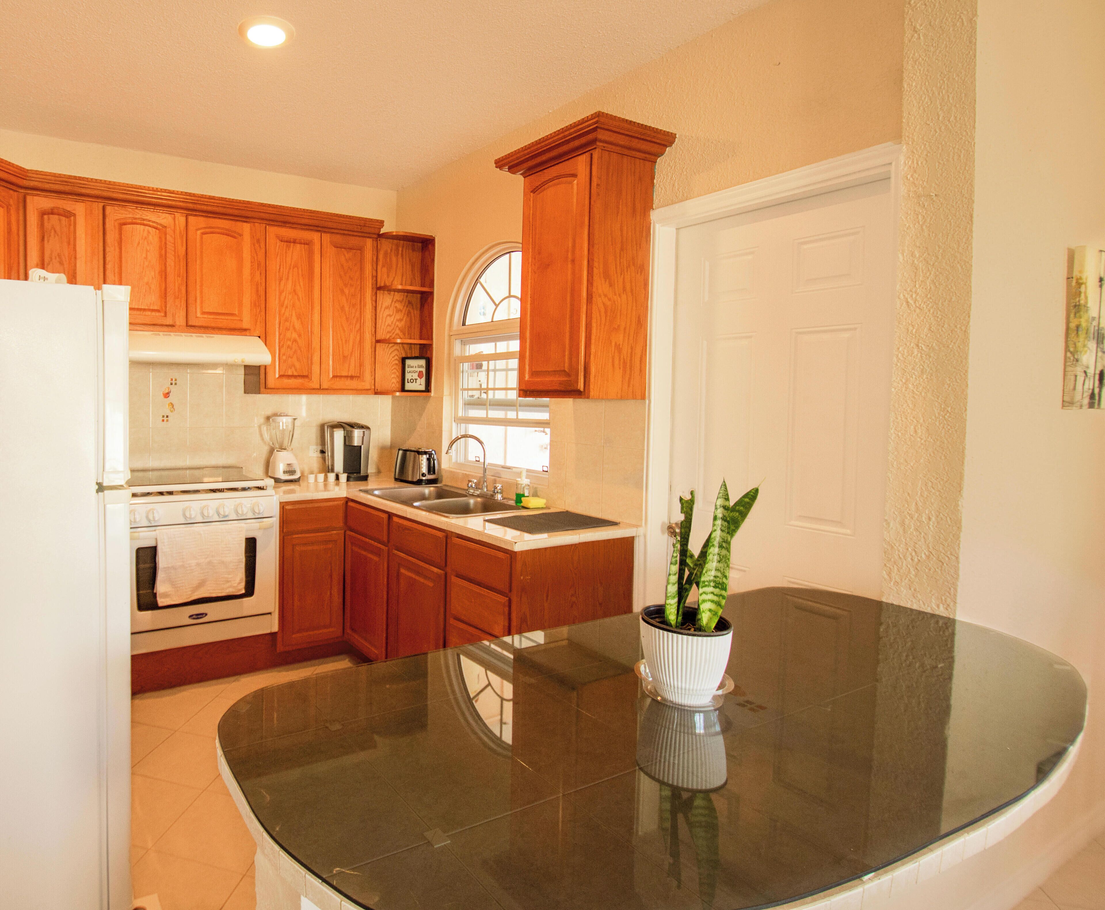 A kitchen with wooden cabinets, a white refrigerator, a stove, a sink, and a window.