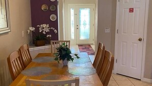 Uma sala de jantar com uma mesa de madeira, cadeiras e um vaso de flores.
