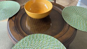 Une table à manger avec un saladier jaune et des sets de table verts.