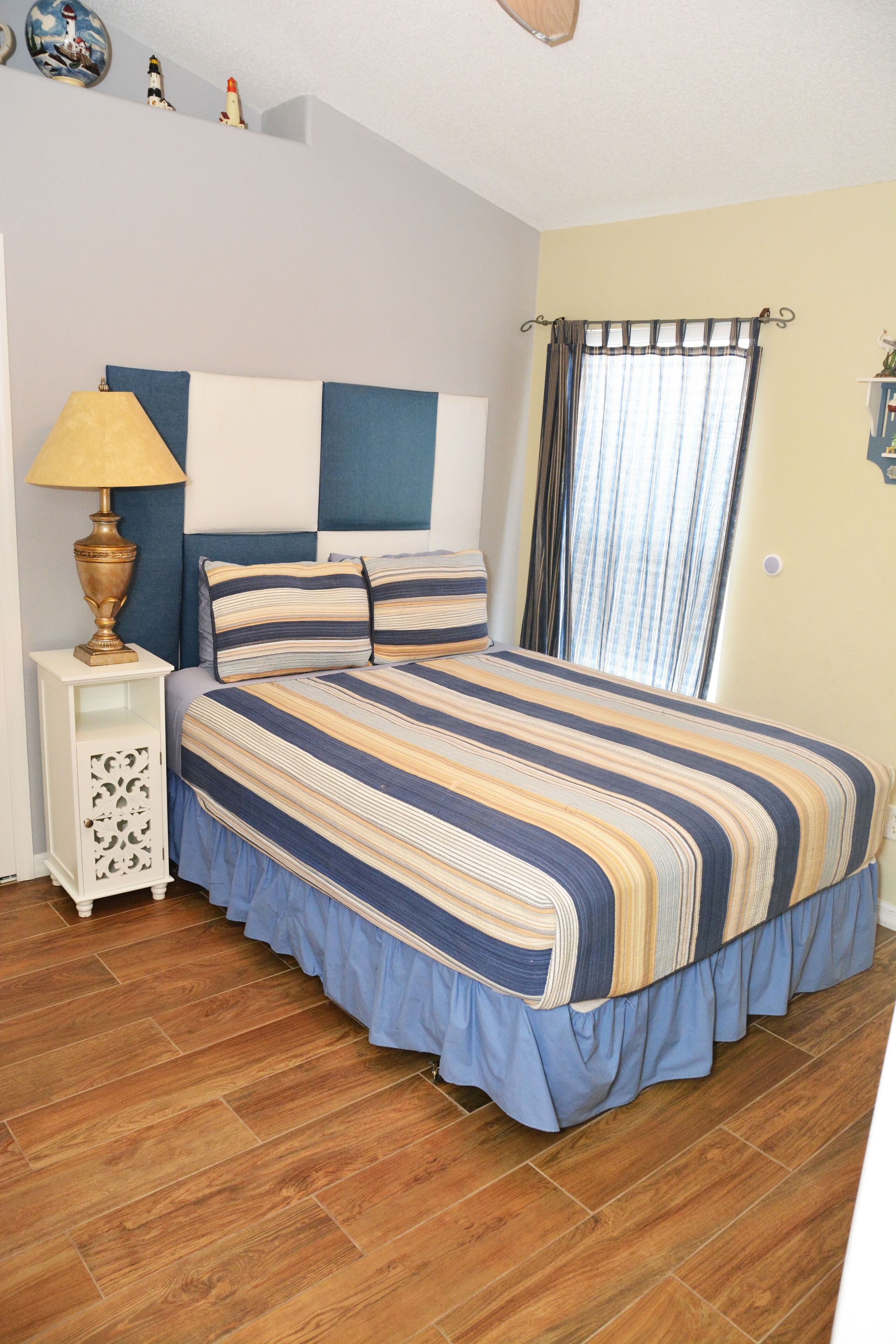 A bedroom with a bed, a nightstand, a lamp, and a window with curtains.